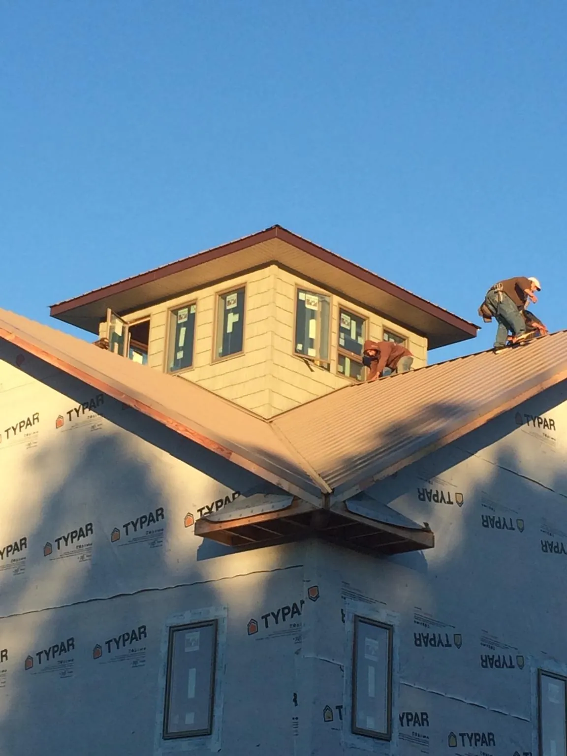 Roofers working around a rooftop cupola on a new metal roof at sunset — Roof Waterproofing in Chandler by Roofing Brothers